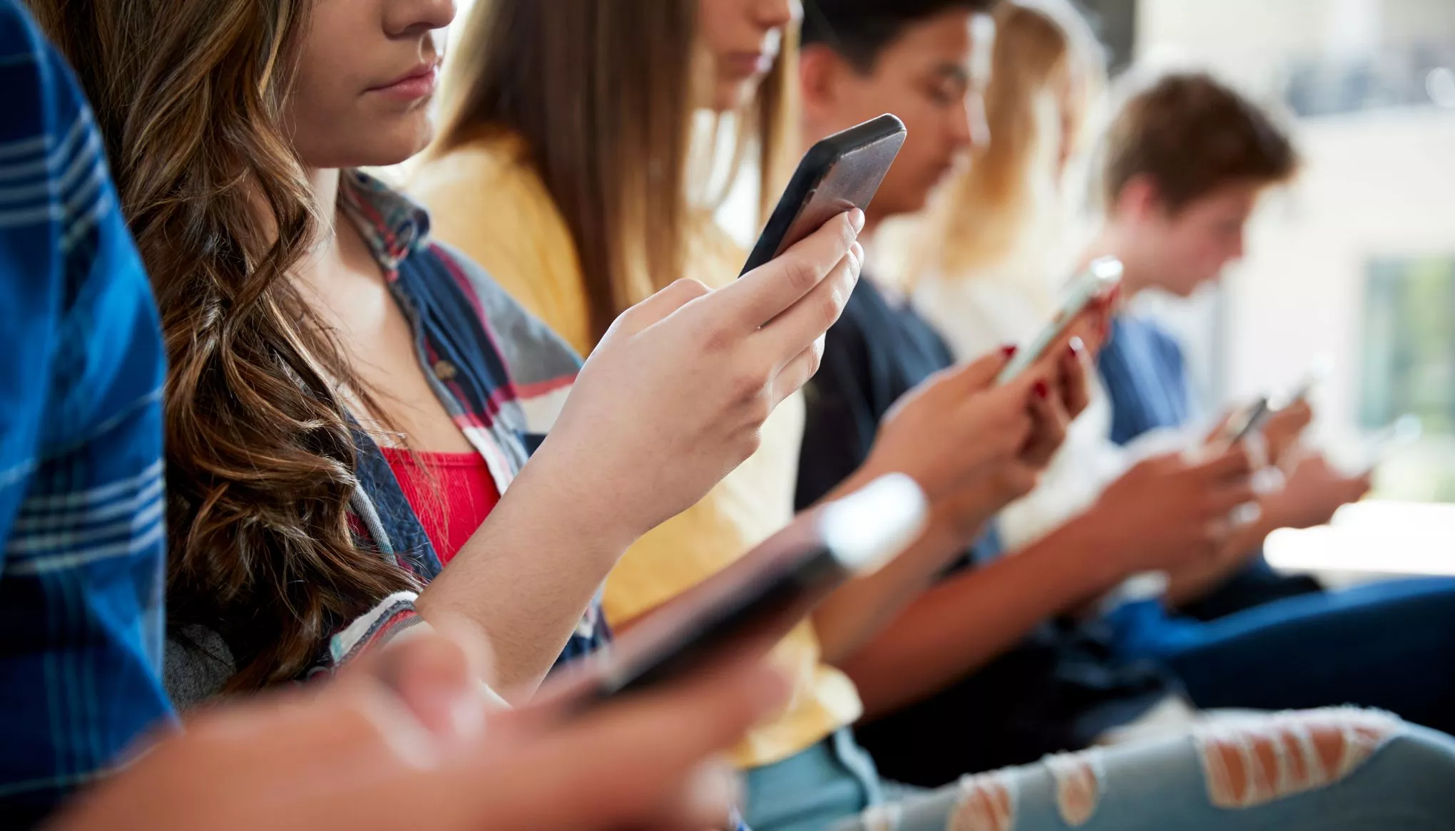 Des jeunes utilisant leur téléphone côte à côte